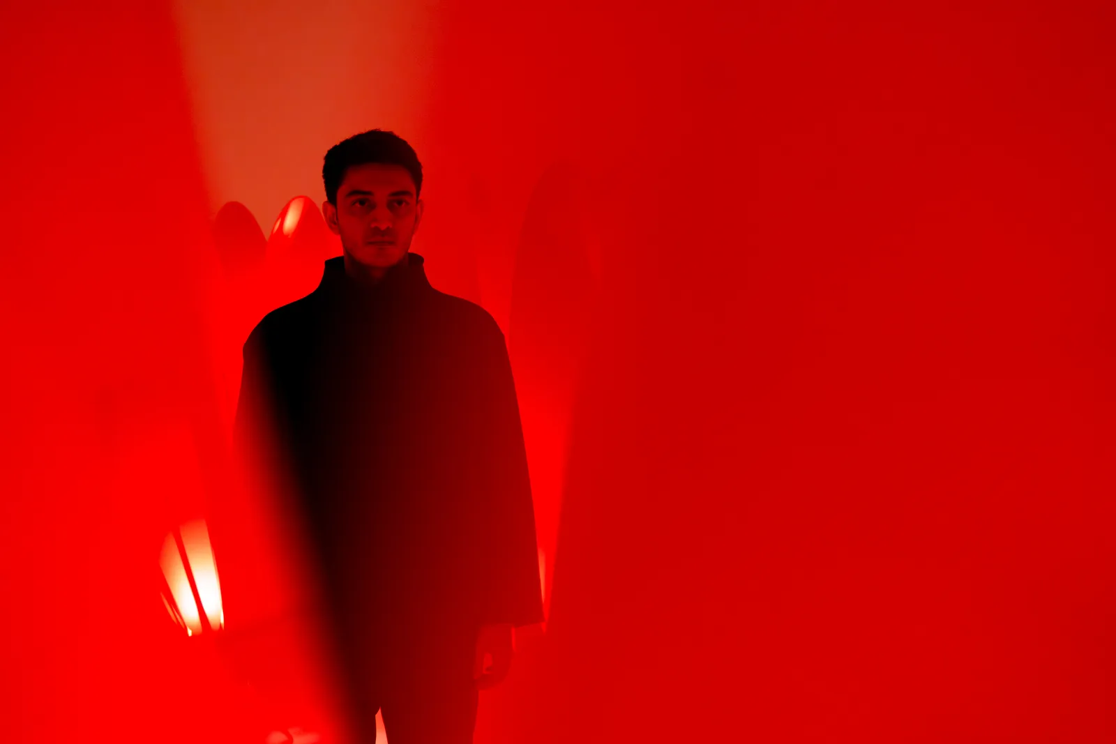 Reza Raeisifar in silhouette, immersed in the red glow of The Crimson Procession