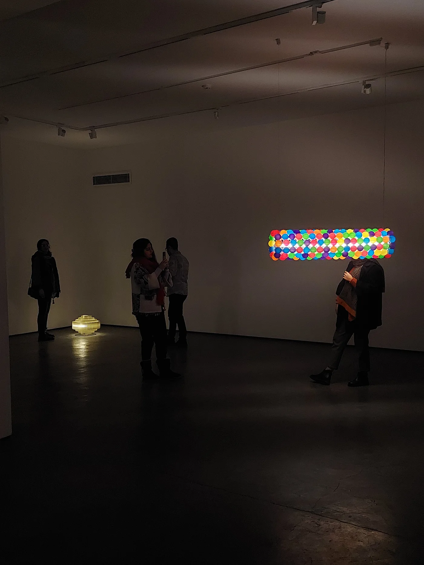 Visitors moving through the darkened gallery