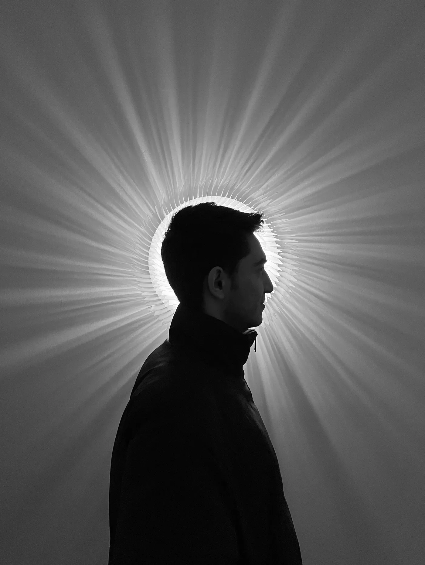 Reza Raeisifar in profile, lit by a radial light work at IranShahr Gallery