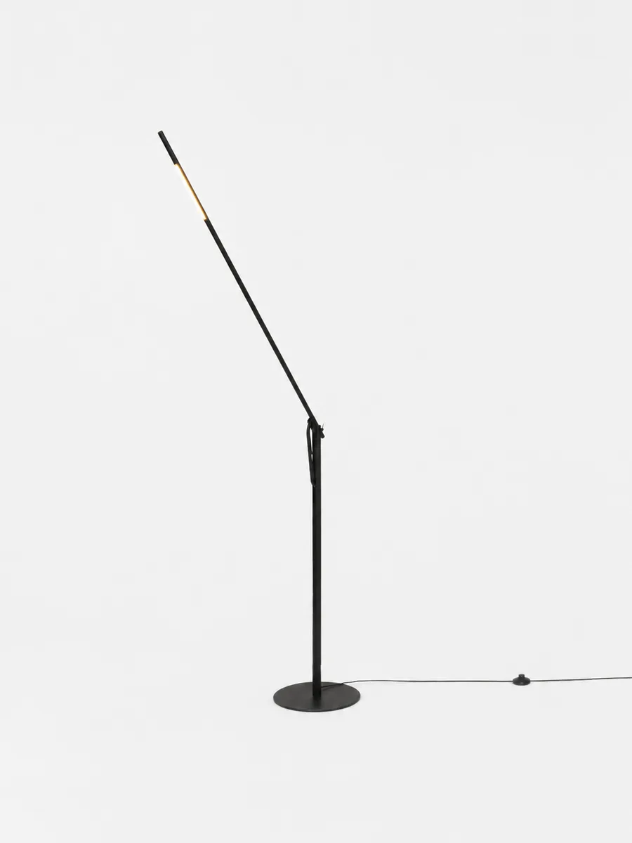The Calibre floor lamp, arm raised, light glowing at its tip