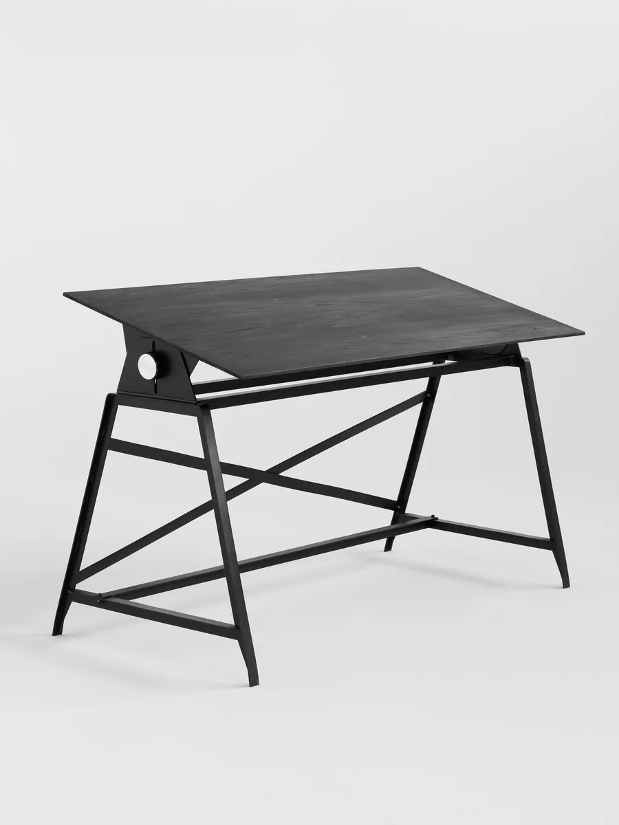The Makran desk with its dark elm top, three-quarter view