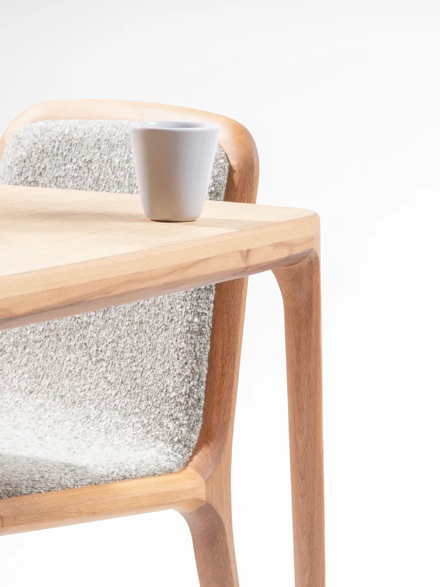 The Maroon dining table up close, a cup resting on its grain