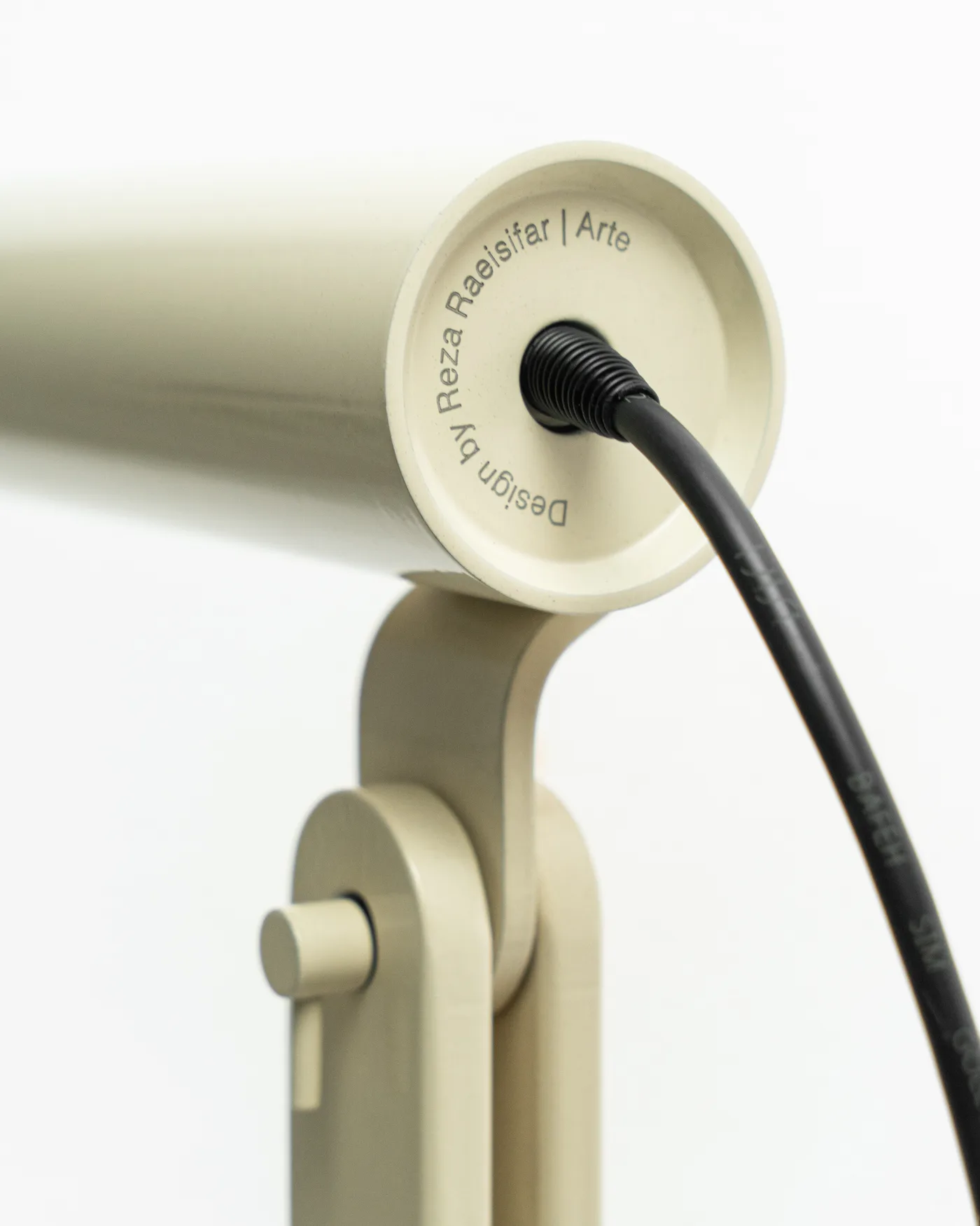 The engraved end cap of the cream Arte, cable curling away