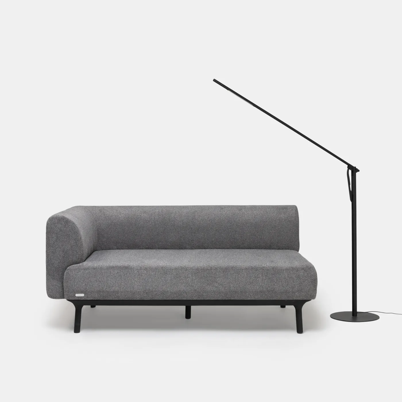 Calibre arcing over a grey chaise, reading light at the ready