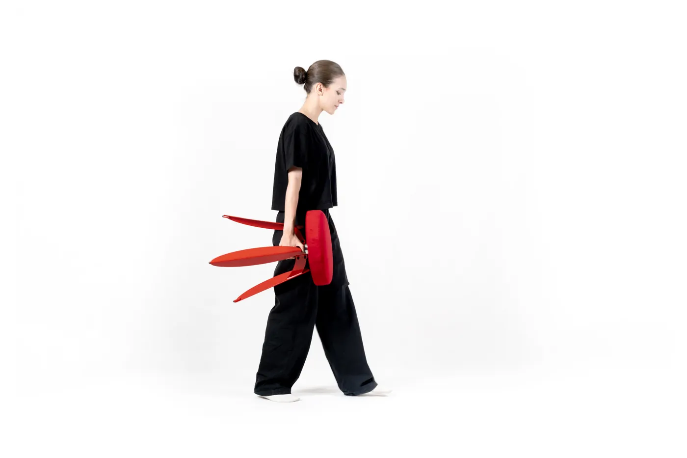 A model carrying the Dot stool's red legs across the studio