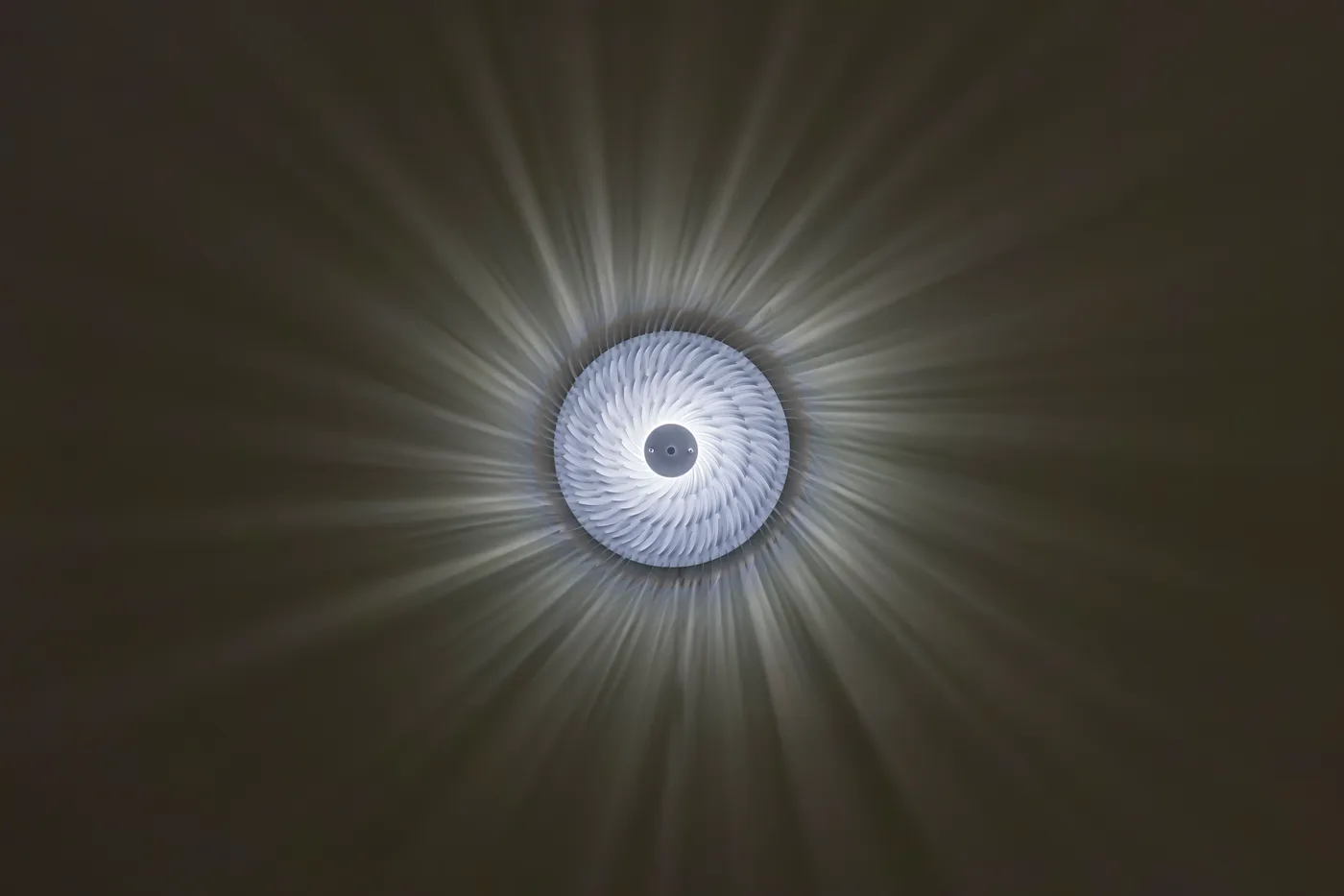 The Keker wall lamp glowing, rays of pleated shadow radiating outward