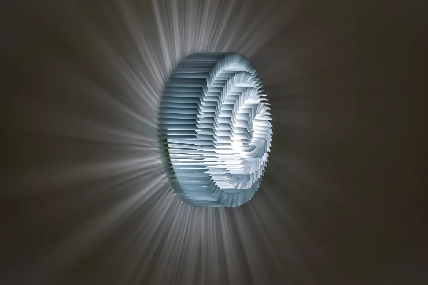 The wall lamp from three-quarter view, its slats spiralling toward the light