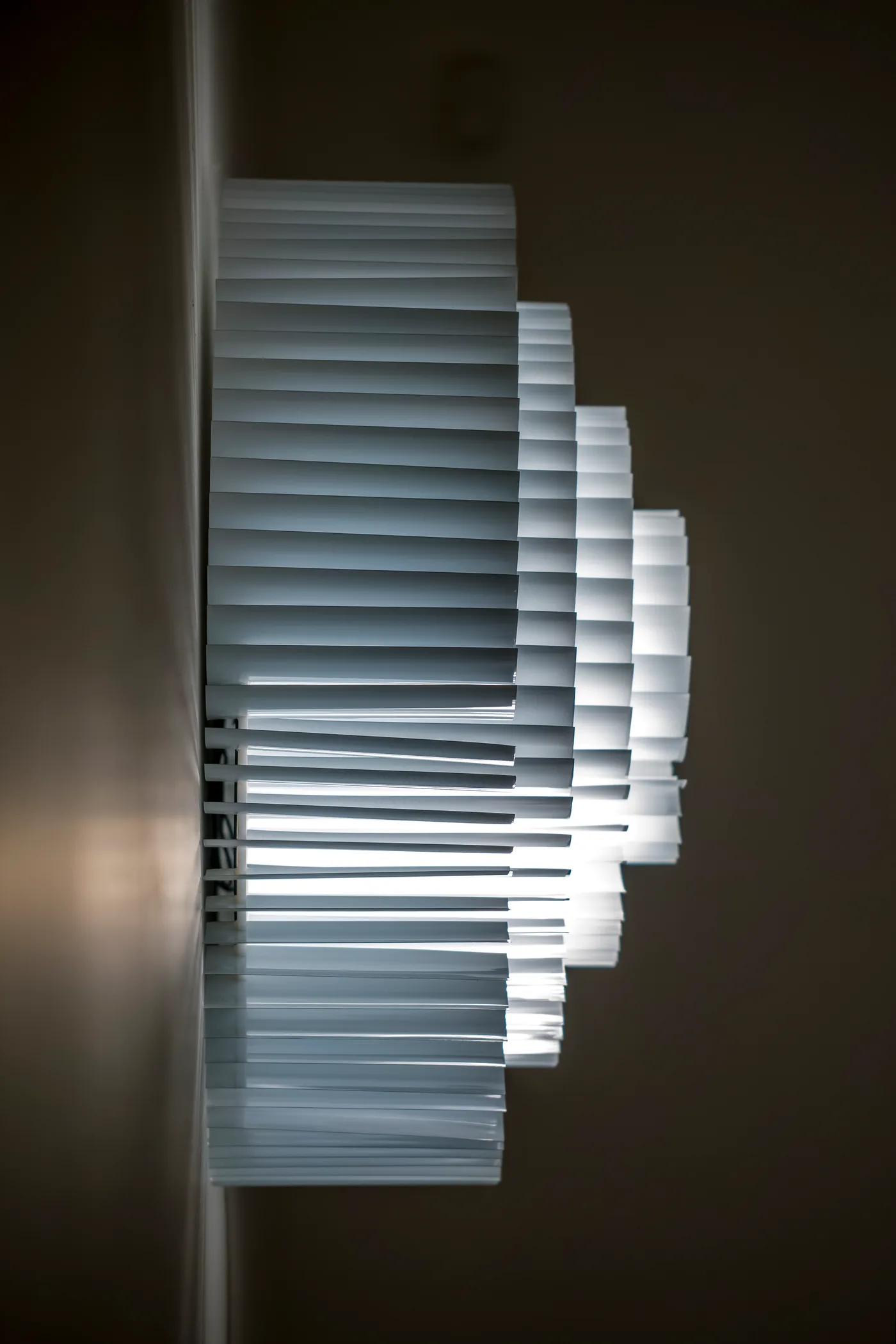 The wall lamp in profile — stepped layers of slats standing off the wall