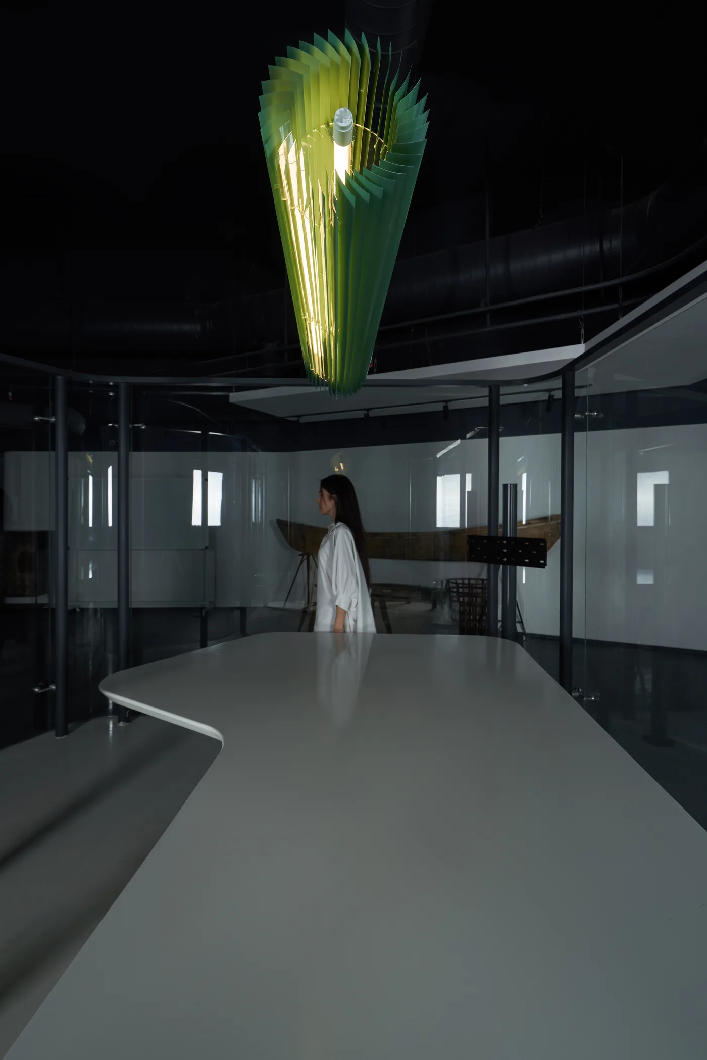 Keker glowing green above a workspace, a figure passing behind glass